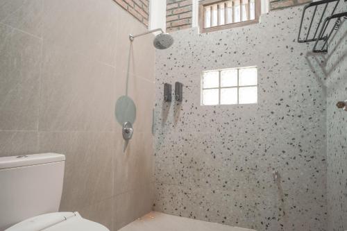 a bathroom with a shower with a toilet and a window at Lingga Garden House in Puncak