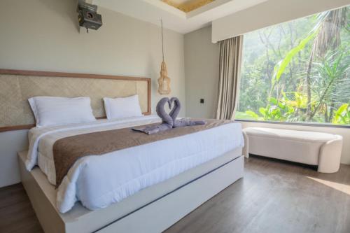 a bedroom with a large bed with a large window at Lingga Garden House in Puncak