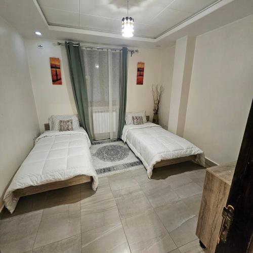 a bedroom with two beds and a window at Joli F3 in Dar el Beïda
