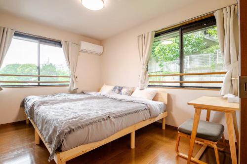 a bedroom with a bed and a desk and windows at B桜坂Sakurazaka APT in Susakiuramachi