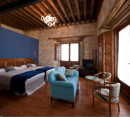 - une chambre avec un grand lit et un canapé bleu dans l'établissement Concejo Hospederia, à Valoria la Buena