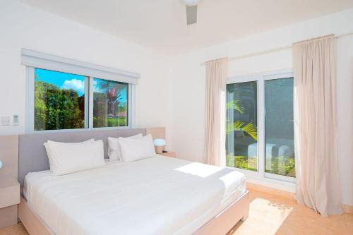 a white bedroom with a large bed and a window at Villa 107 in Sosúa
