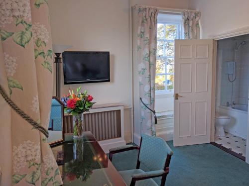 a living room with a vase of flowers and a television at Hook House in Hook