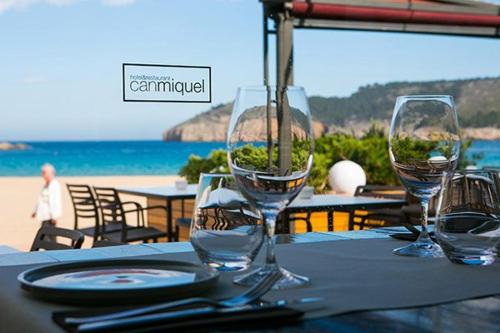 a table with wine glasses on a table at the beach at Can Miquel in L'Escala