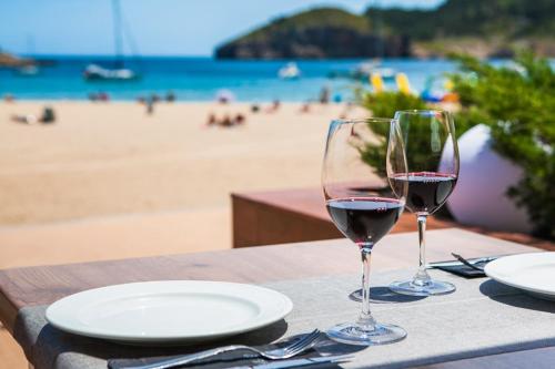 two glasses of wine sitting on a table near the beach at Can Miquel in L'Escala