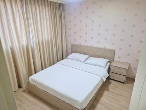 a small bedroom with a white bed and a night stand at Muju Ilsung Condo in Muju