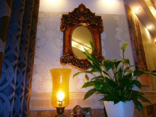 a mirror on a wall with a plant and a lamp at Art Apartments in Poznań