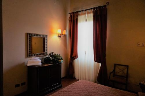 a bedroom with a bed and a mirror and a window at Agriturismo Antico Borgo Poggitazzi in Loro Ciuffenna