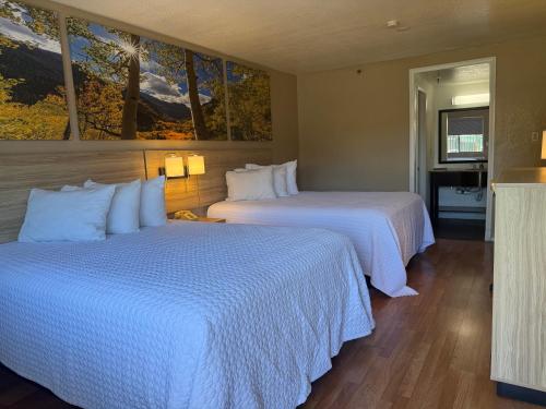 two beds in a hotel room with white sheets at Days Inn by Wyndham Victorville - Hesperia I-15 Palmdale Road in Victorville