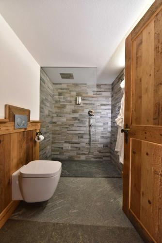 a bathroom with a toilet and a stone wall at L'Ancien Paquier Chambre D'Hotes in Valtournenche