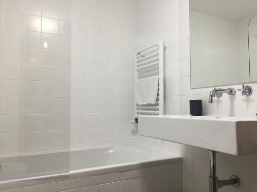 a white bathroom with a sink and a bath tub at Casas do Teatro in Porto