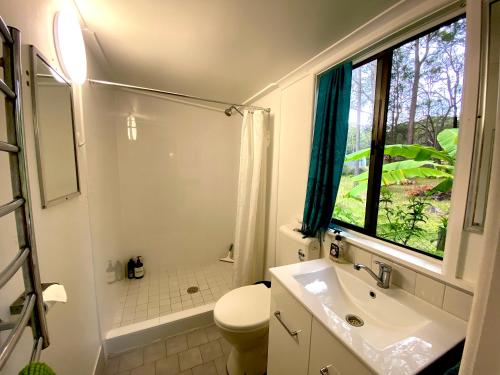 a bathroom with a sink and a toilet and a window at Lakeside 3-BR Forest Cottage in Laurieton