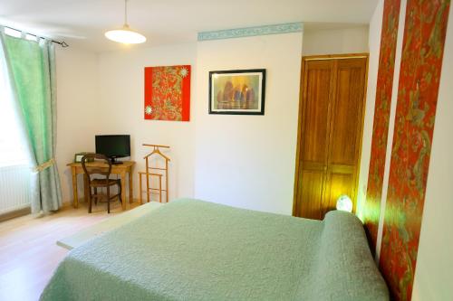 a bedroom with a bed and a desk with a computer at Logis Auberge La Cremaillere in Villandraut