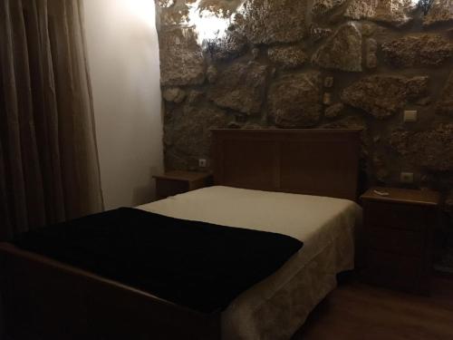 1 dormitorio con cama y pared de piedra en Casa de Basto, en Celorico de Basto