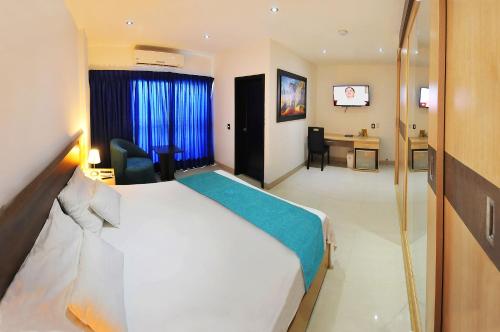 a hotel room with a large bed and a desk at Hotel Campestre El Cisne in Barranquilla