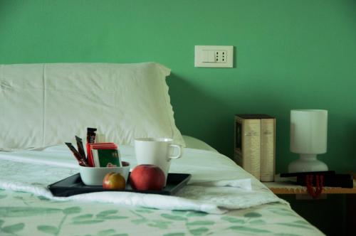 a tray with fruit and a cup on a bed at Cascina delle Mele in Vittuone