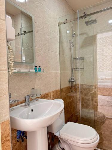 a bathroom with a toilet and a sink and a shower at Muxlis Hotel in Tashkent
