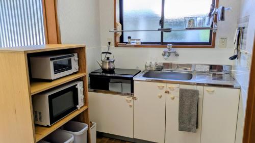 a small kitchen with a sink and a microwave at 那智温泉 南の湯 - Nachi Manga Onsen in Nachikatsuura
