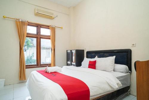 a bedroom with a large bed with a red blanket at RedDoorz near Universitas Merdeka Malang 2 in Malang