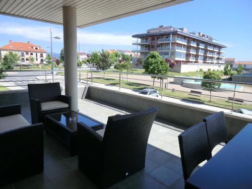 balcón con sillas y vistas a un edificio en APARTAMENTOS DE CANELAS SUITES con AMPLIAS TERRAZAS, en Portonovo