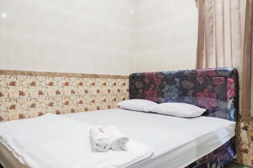 ein Bett mit zwei weißen Handtüchern darauf in der Unterkunft Queen Asri Mitra RedDoorz in Kediri