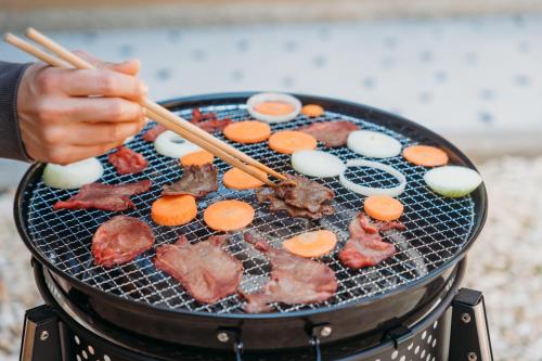 a person cooking food on a grill with chopsticks at 囲み宿 こわね in Tonosho