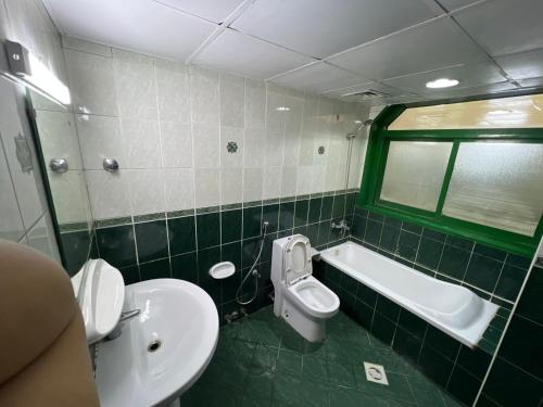 a bathroom with a toilet and a tub and a sink at ALEX Hostel C2602 - Bed in Shared Room for Males in Sharjah