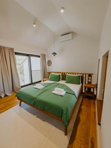a bedroom with a green bed and a large window at Up and above in Kobarid