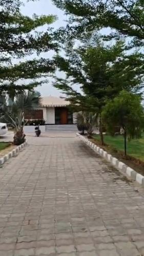 a brick road with trees in front of a building at Suryansh Outhouse in Jaipur