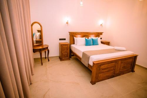 a bedroom with a bed and a desk and a mirror at King Palace Mirissa in Mirissa