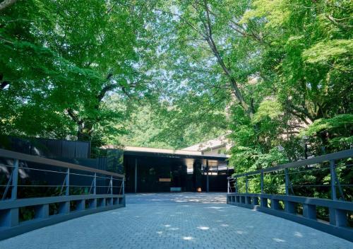 a bridge in a park with trees and a building at Fufu Atami in Atami