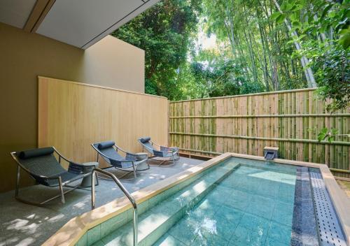 a swimming pool with two chairs and a fence at Fufu Atami in Atami