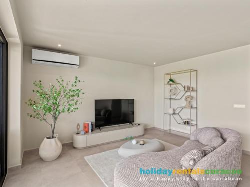 a living room with a couch and a tv at Luxury Two-Bedroom Apartments at Blue Bay The Breeze in Dorp Sint Michiel