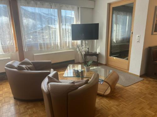 a living room with chairs and a table and a tv at Fantastic view, cosy flat in chalet Bergfink in Grindelwald