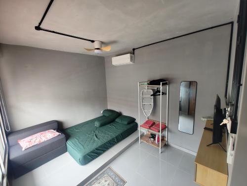 a small room with a green bed and a mirror at Tein roomstay in Rengit