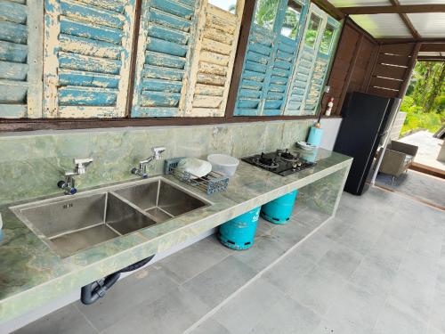 a kitchen with a sink and a counter with windows at Tein roomstay in Rengit