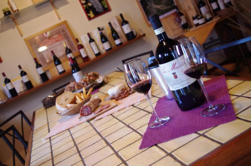 a bottle of wine sitting on a counter with wine glasses at Cascina Bertolotto Wine Resort in Spigno Monferrato