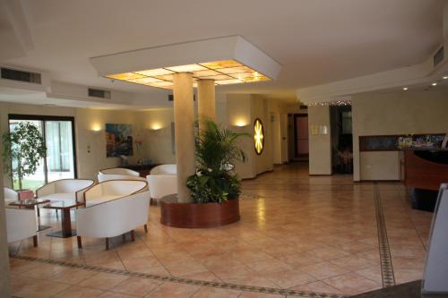 a lobby with white chairs and a potted plant at Hotel Porto Azzurro in Sirmione