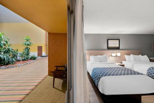 a hotel room with two beds and a hallway at Suburban Studios, Kearney in Kearney