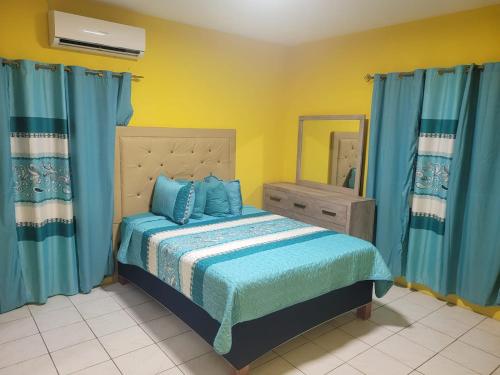 a bedroom with a bed with blue sheets and a mirror at Enchanted Guest House & Hostel in Ocho Rios