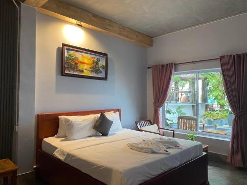 a bedroom with a bed and a window at The Coconut House Hotel in Battambang
