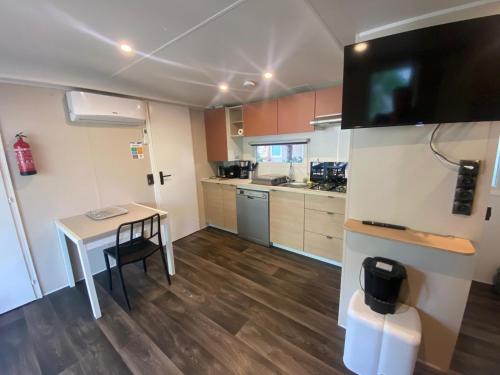 a kitchen with a table and a tv on a wall at Camping Mayotte, Biscarosse in Biscarrosse