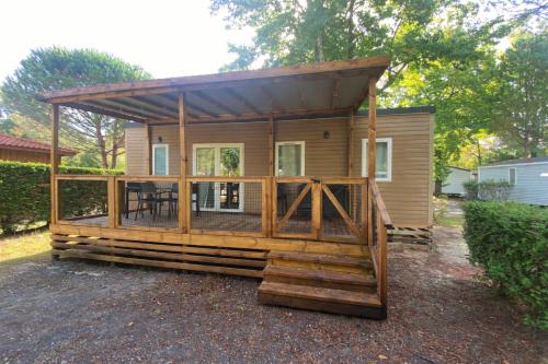 a log cabin with a roof over a deck at Camping Mayotte, Biscarosse in Biscarrosse
