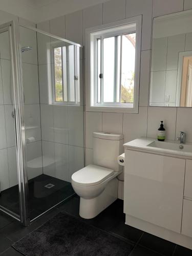 a white bathroom with a toilet and a sink at Happy Mountain House in Blackheath