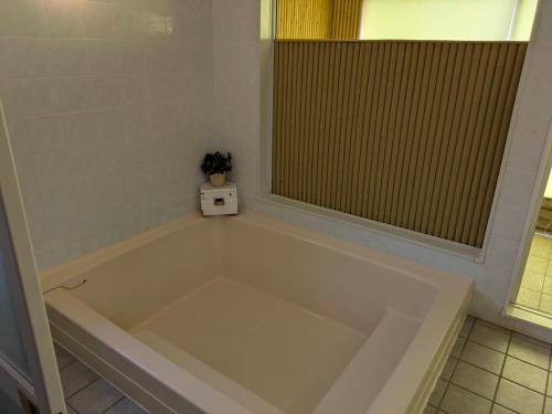 a large bath tub in a bathroom with a window at ラシェール 伊豆 ガーデンテラス AWA Resort in Ito