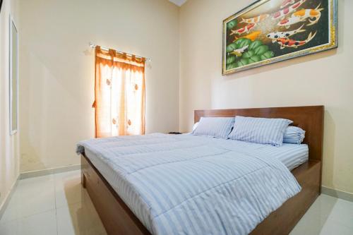 a bedroom with a bed with a blue striped blanket at Villa Maurine Prambanan in Jogonalan