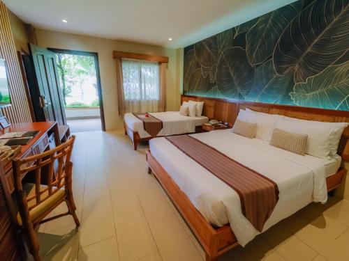 a hotel room with two beds and a desk at Bohol Beach Club in Panglao Island