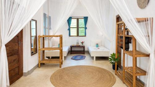 a room with white curtains and a table and a bed at New Teddy's on the Beach in Jambiani