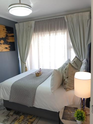 a bedroom with a bed with white sheets and a window at URlyfstyle Kikuyu Escape Waterfall Mall of Africa in Midrand