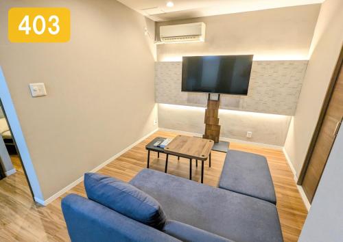 a living room with a blue couch and a tv at Chateau Sunrise in Tokyo